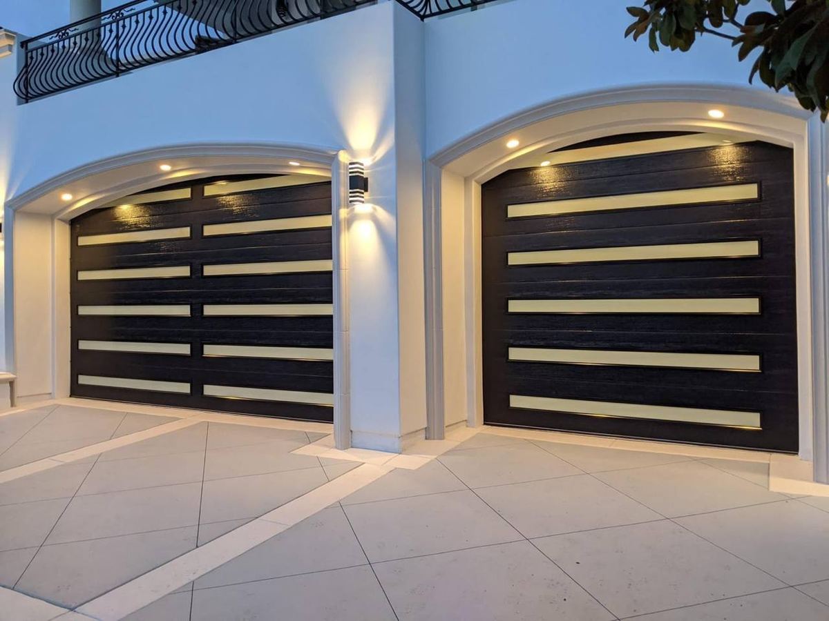 Pair of modern black garage doors installed on a stucco home